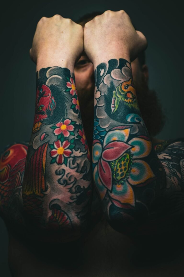 Due avambracci coperti di tatuaggi old school colorati con fiori e carpe koi